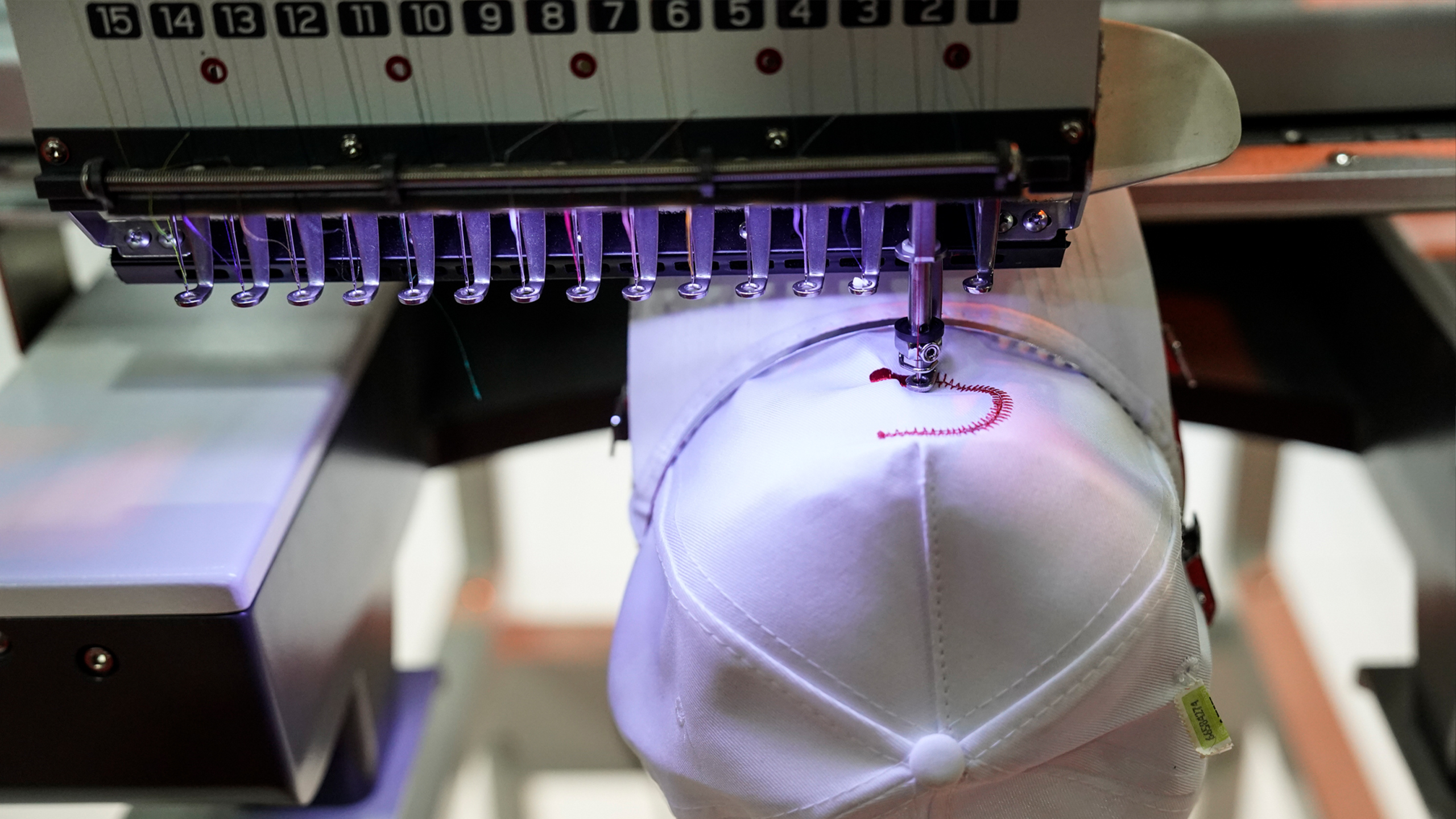 Foto de máquina bordando una figura en una gorra blanca durante Confemaq